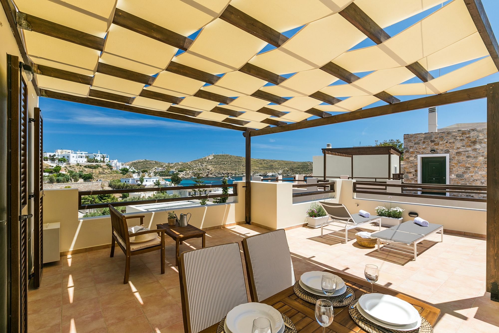 A spacious sea view veranda with pergola, furnished with lounge, two sunbeds and dining table.