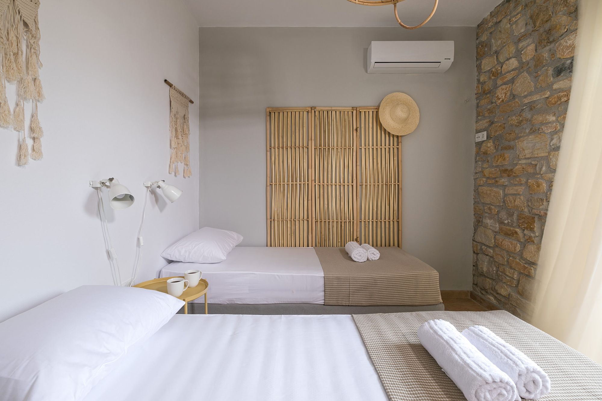 A twin bedroom of a stone-built residence decorated in boho style and in earth tones.      