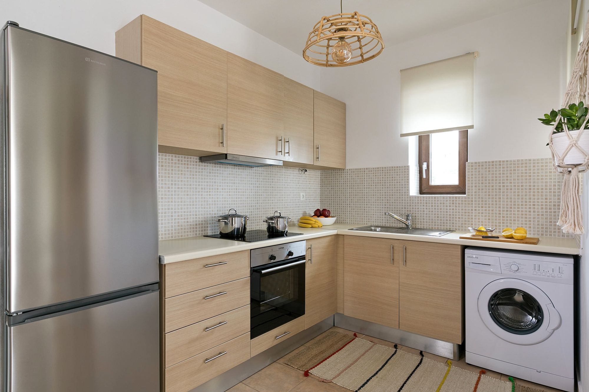 Modern kitchen with beige cabinets, a big inox fridge, an electric cooker oven and a washing machine.