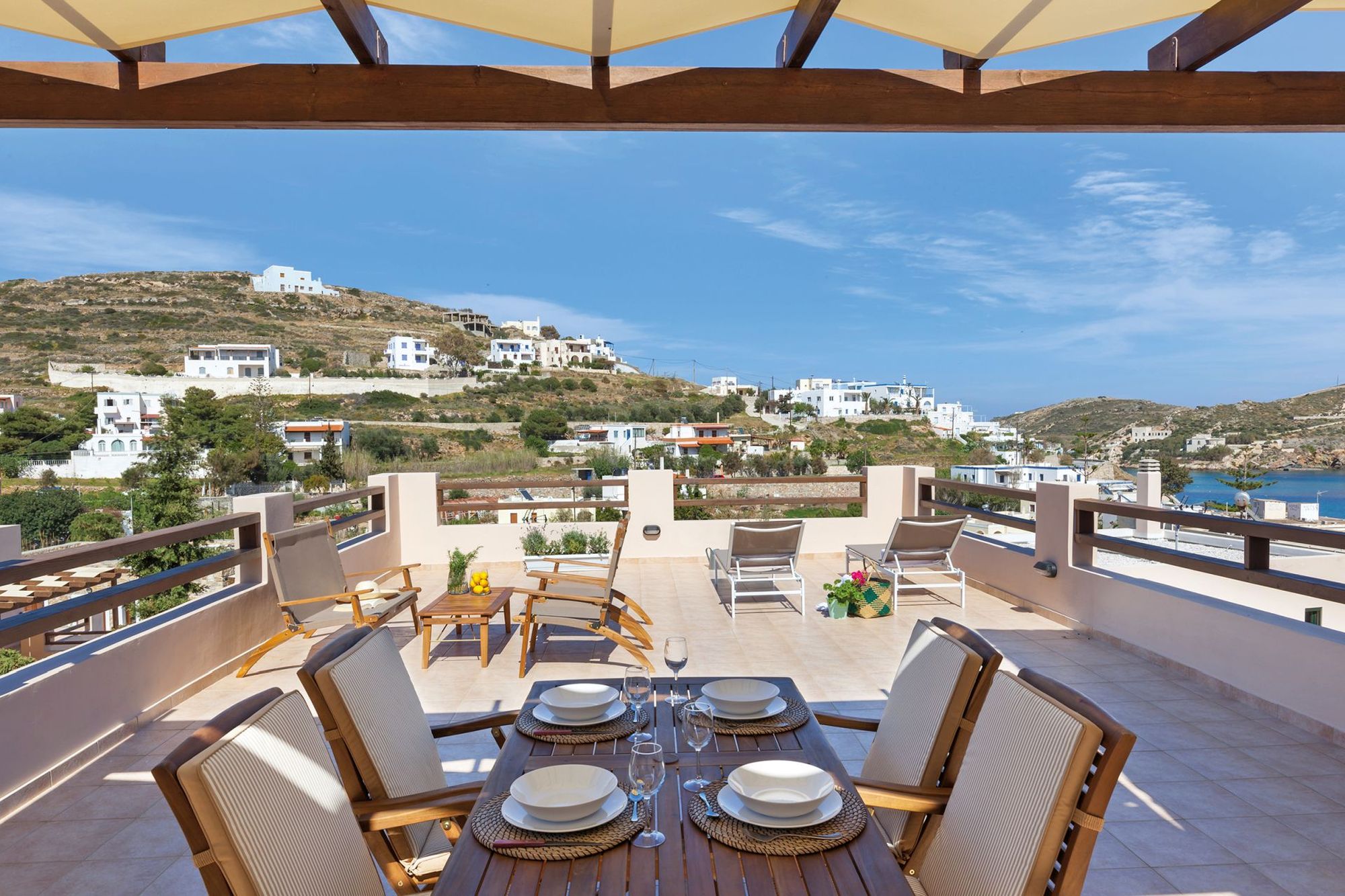 Spacious sea view veranda with pergola fully furnished with a dining table, a lounge and two sunbeds.
