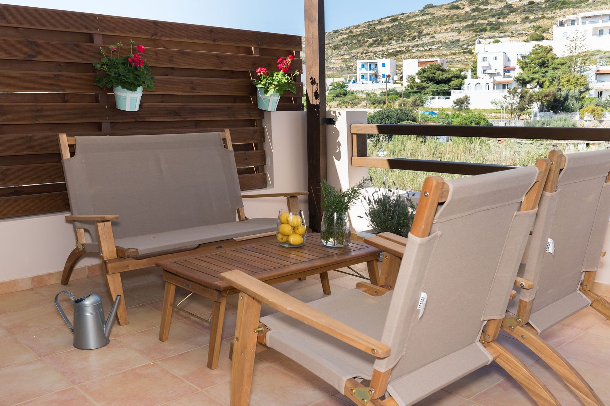 Veranda with beautiful flowerpots furnished with a sofa, a coffee table and two armchairs. 