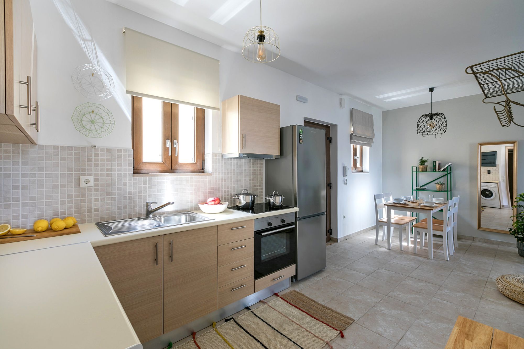 Modern and fully equipped kitchen with a big inox fridge, an electric cooker oven and a dining table in same space.