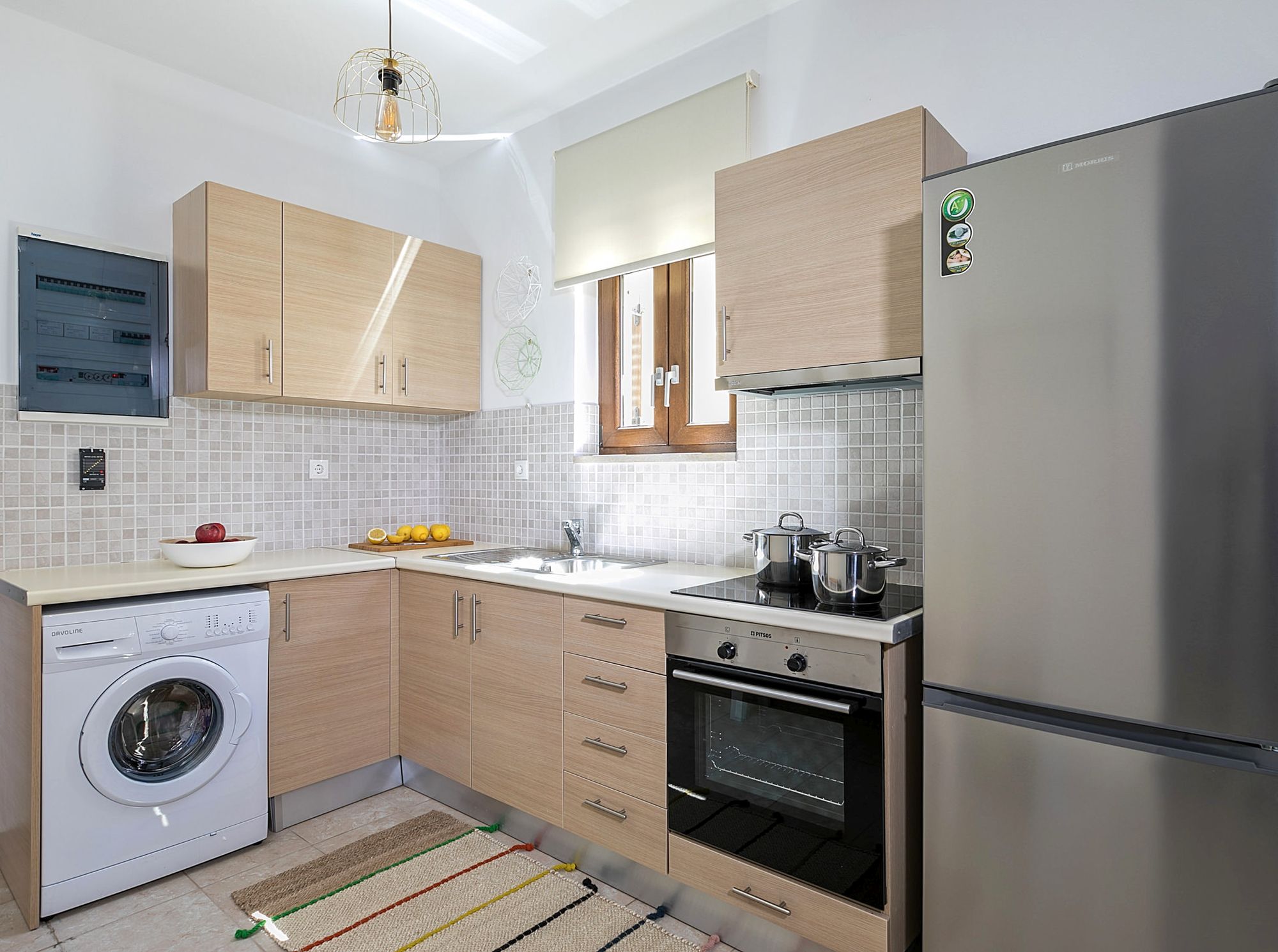 Fully equipped kitchen with an inox big fridge, an electric cooker oven and a washing machine.