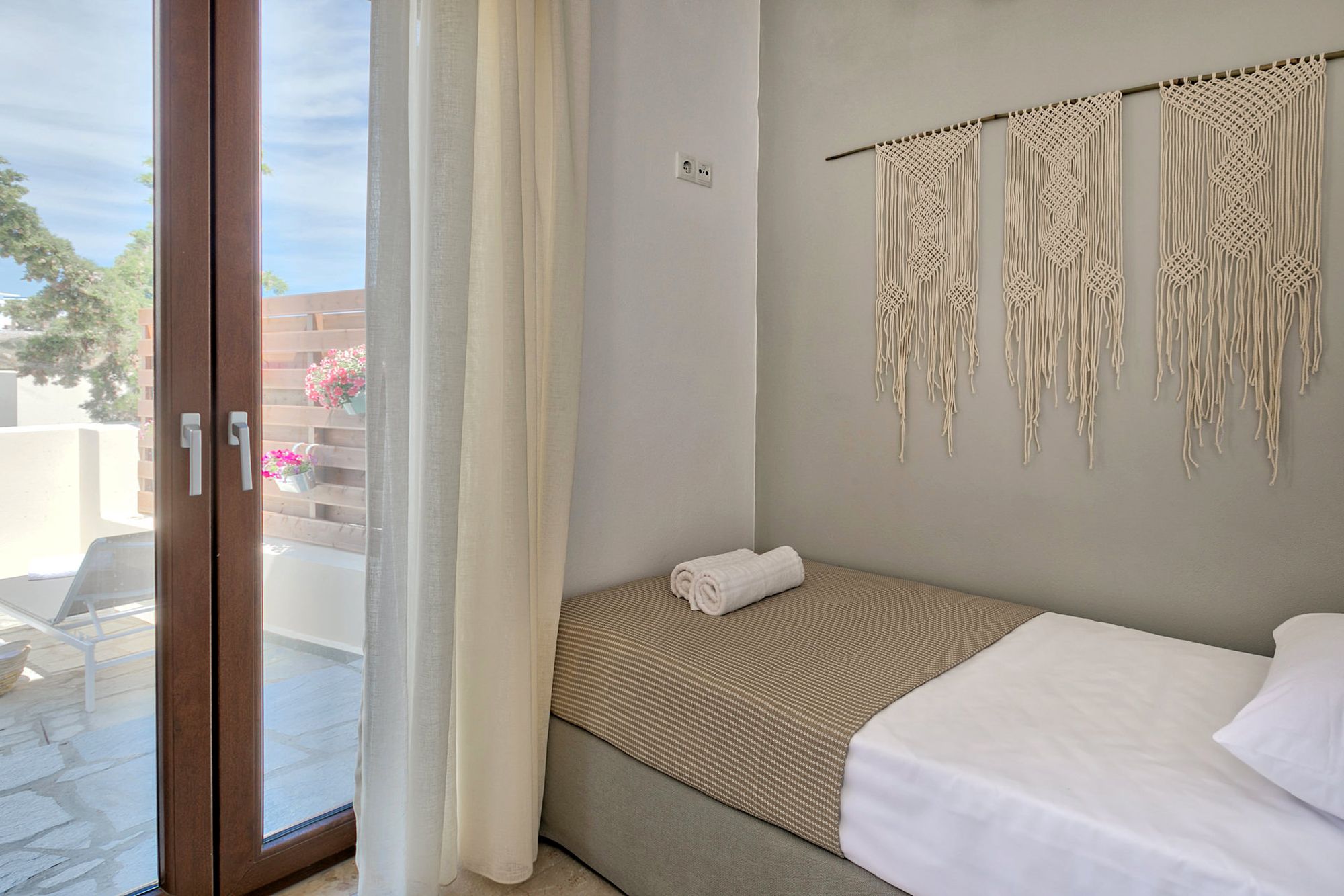 Bedroom with one single bed and a white decorative macramé on the wall next to the bed. 