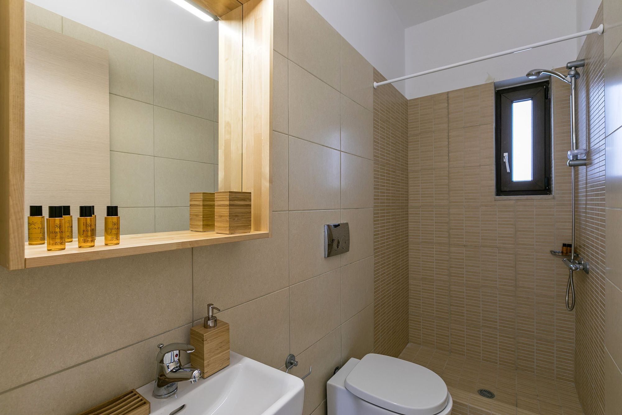 Μοντέρνο μπάνιο με ντουζιέρα και μεγάλο ξύλινο καθρέφτη πάνω από τον λευκό νιπτήρα.