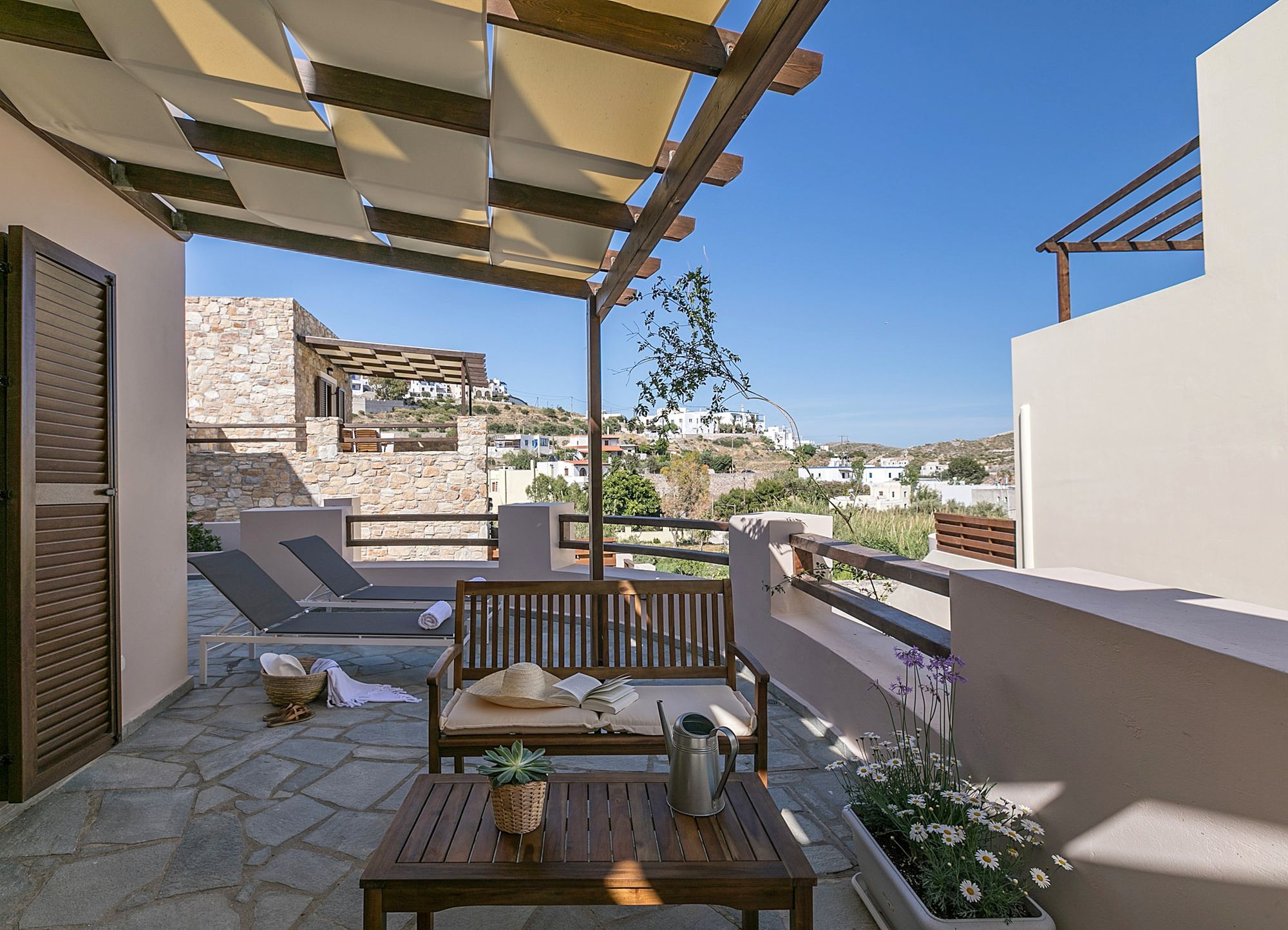 Veranda furnished with two sunbeds, a wooden sofa and a coffee table with a nice flowerpot on it.