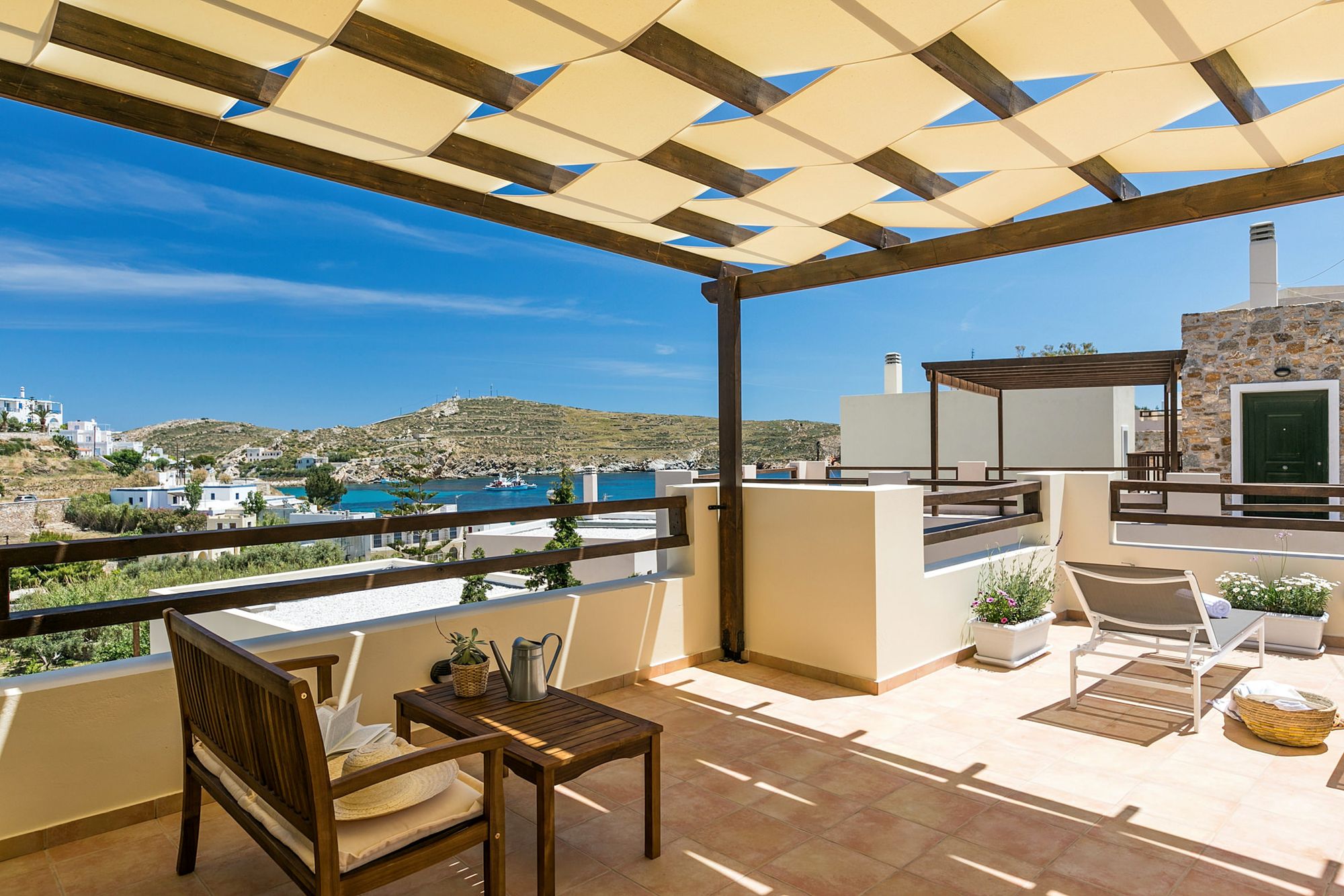 Spacious sea view veranda with pergola, lounge, two sunbeds and flowerpots.