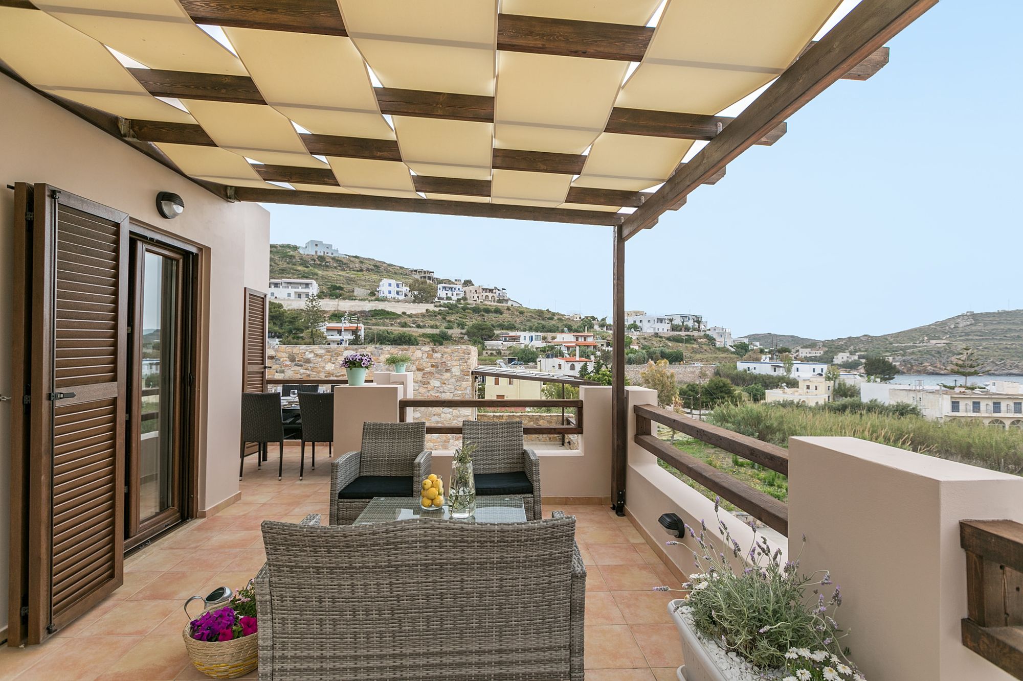 Veranda with pergola, fully furnished with a lounge, a dining table and beautiful flowerpots.