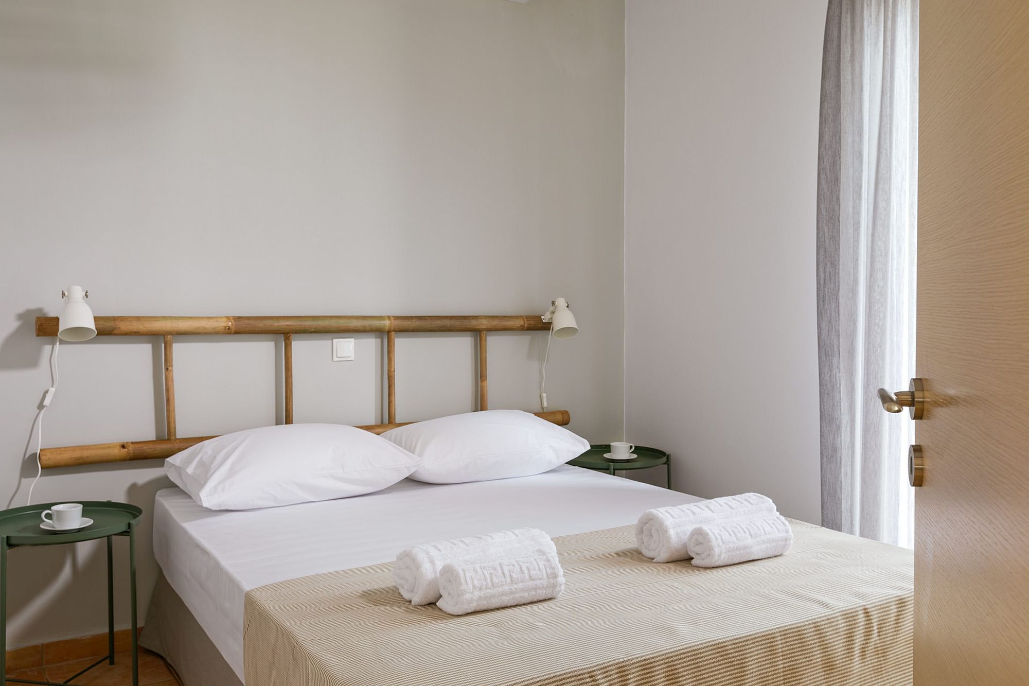 Υπνοδωμάτιο με διπλό κρεβάτι, μεταλλικά πράσινα κομοδίνα, μοντέρνα λευκά σποτάκια και διακοσμητική ξύλινη σκάλα στον τοίχο πάνω από το κρεβάτι.
