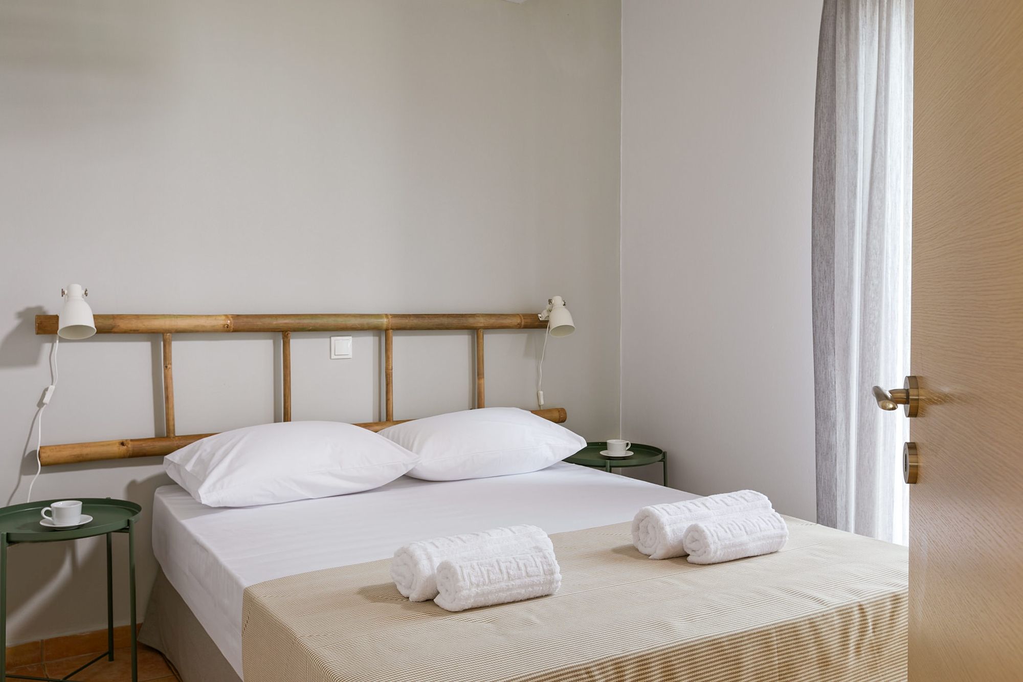 Bedroom with a double bed, two green metallic bedside tables, modern white wall lights and a decorative wooden ladder on the wall over the bed.