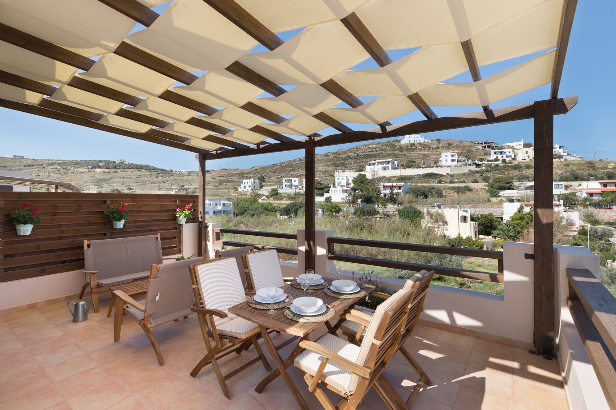 Veranda with pergola furnished with lounge and dining table with four chairs.