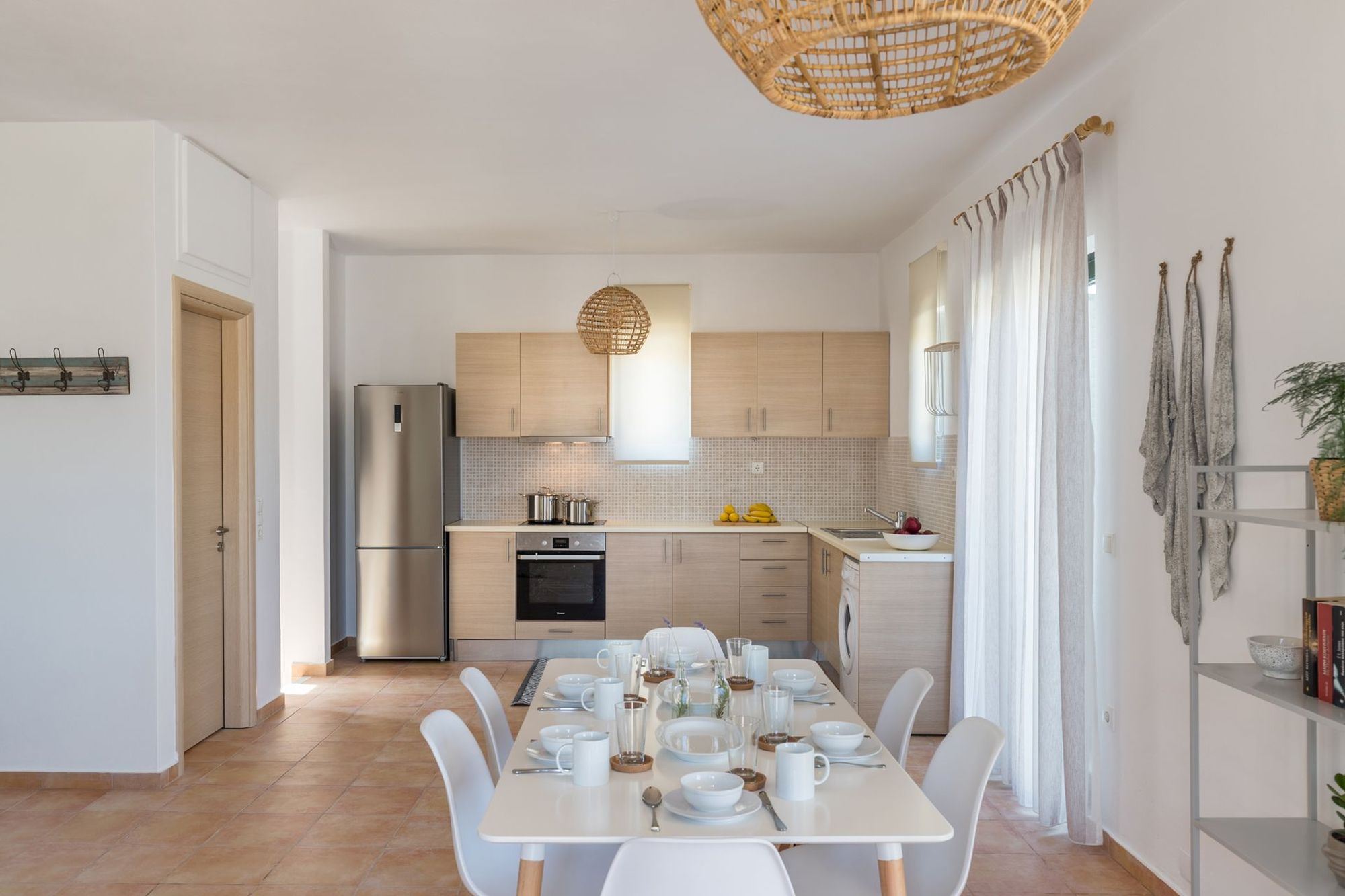 The kitchen and the white dining table of a residence decorated in earth tones.